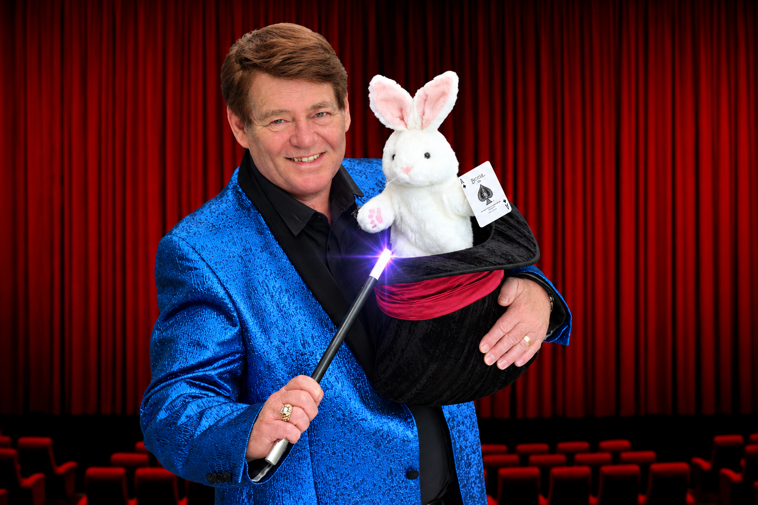 Alan Watson with a magic wand and a toy rabbit in a top hat on stage